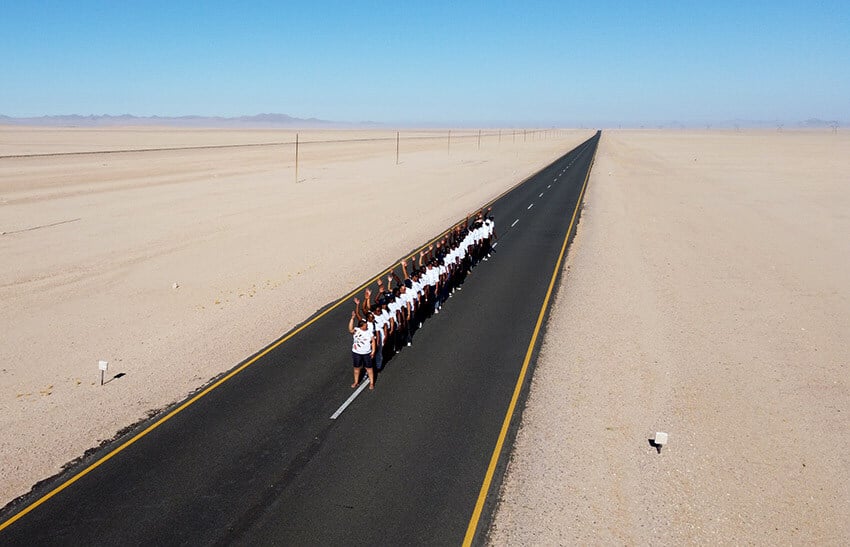Group of people on middle line of long road, desert, Namibia