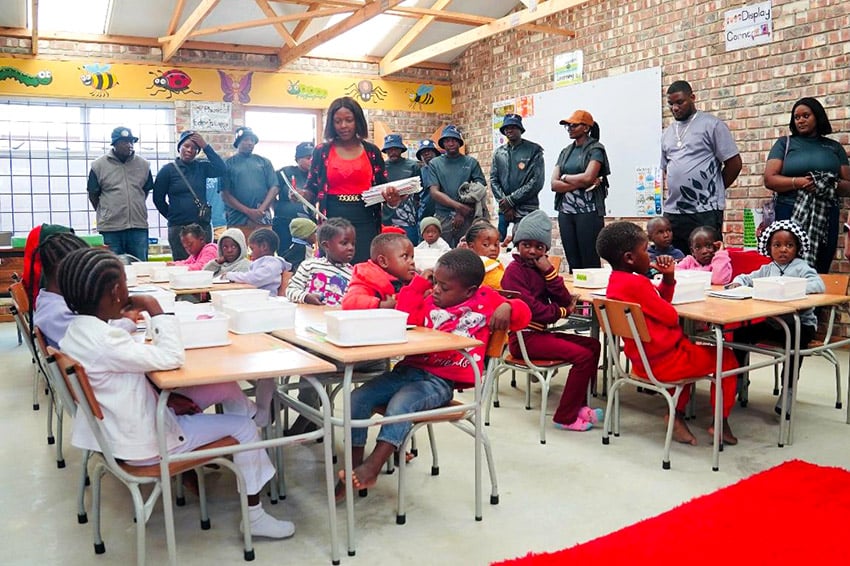 Cuildren around tables, adults watching, Namibia 